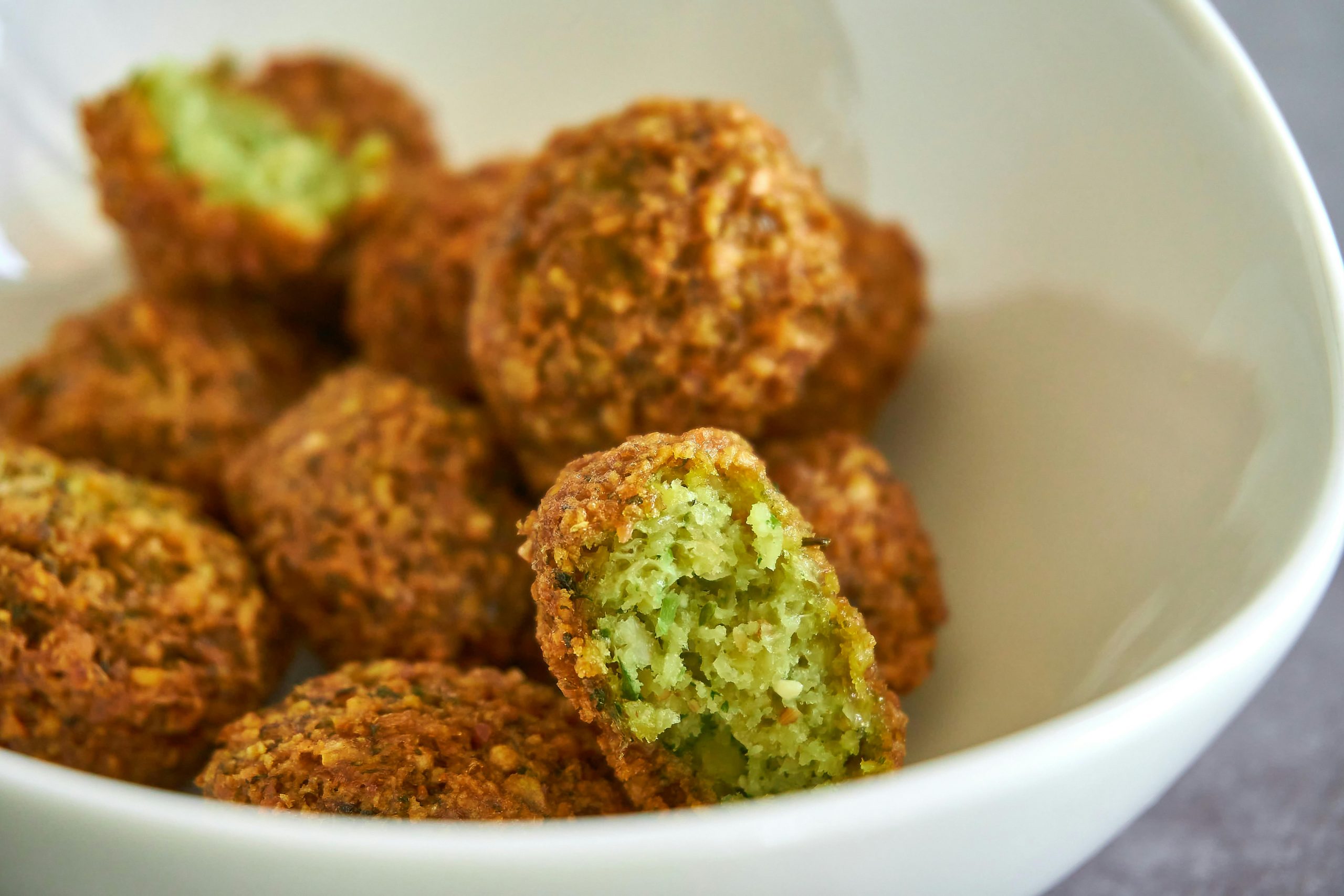 Close-up of golden-brown falafel in a bowl, showcasing texture and freshness.